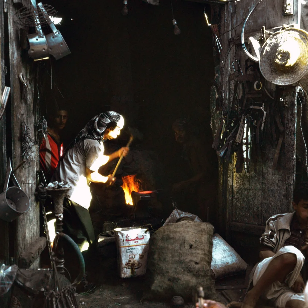 Fragua encendida en un taller de cuchillería con herramientas de forja colgadas alrededor del yunque
